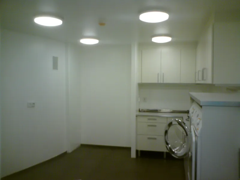Ljust kök och tvättutrymme med vita väggar